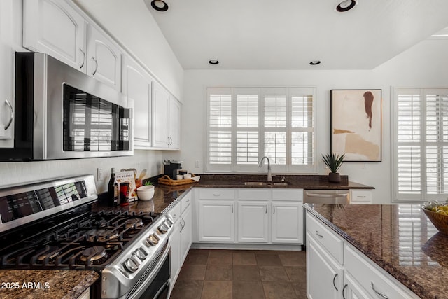 kitchen with sink, white cabinetry, dark tile patterned flooring, dark stone countertops, and stainless steel appliances