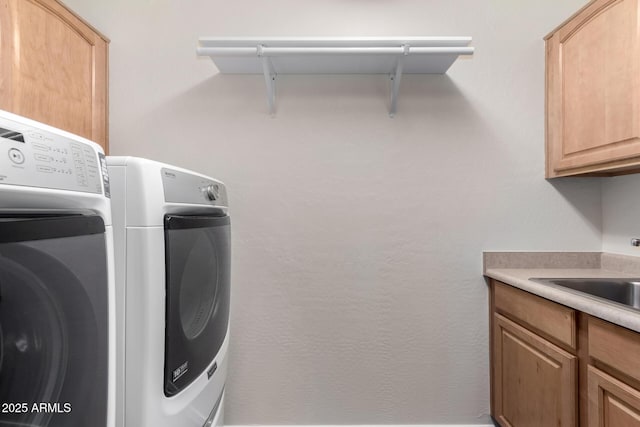 laundry room with sink, washing machine and clothes dryer, and cabinets