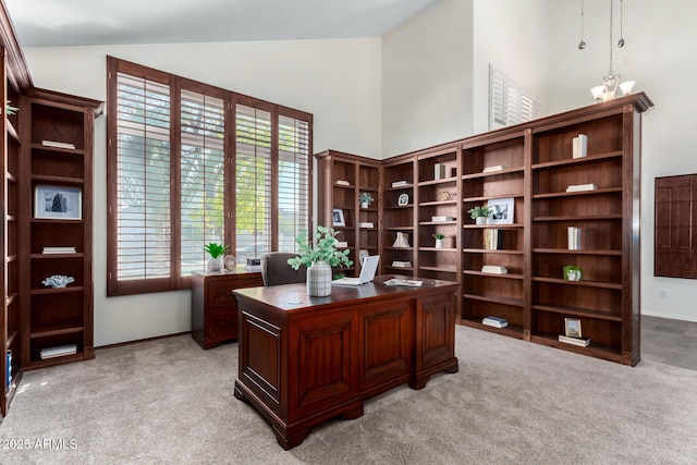 carpeted office space featuring a chandelier and high vaulted ceiling