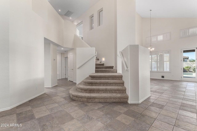 stairs with a chandelier and a towering ceiling