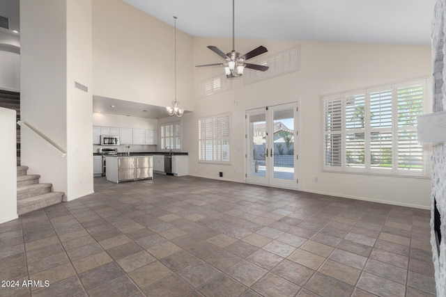 unfurnished living room with ceiling fan and a high ceiling