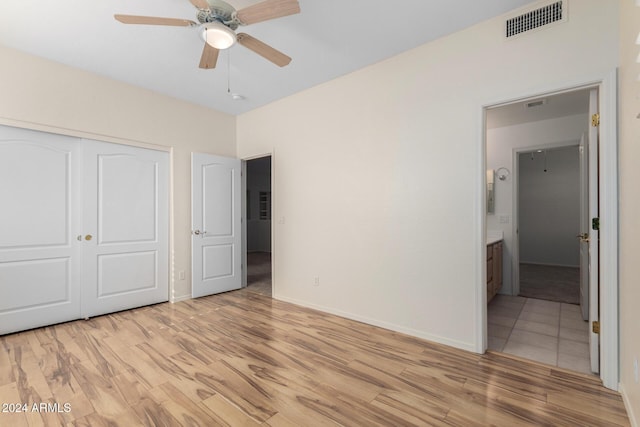 unfurnished bedroom featuring light hardwood / wood-style floors, a closet, ceiling fan, and connected bathroom