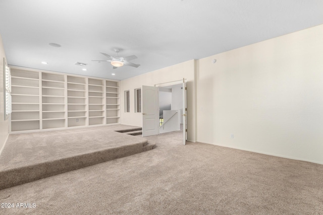 empty room with ceiling fan, built in features, and carpet