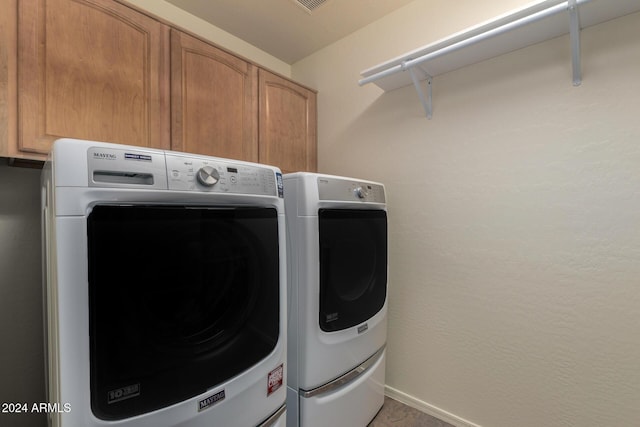 washroom with washer and dryer and cabinets