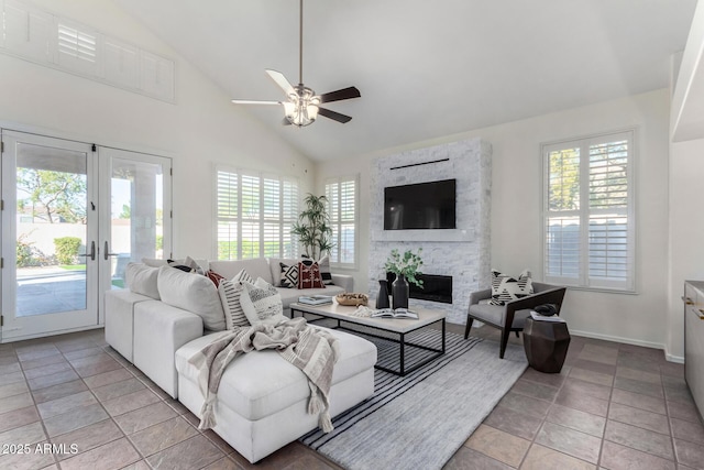 tiled living room featuring high vaulted ceiling, ceiling fan, french doors, and a stone fireplace