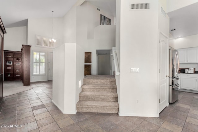 stairs with a high ceiling and an inviting chandelier