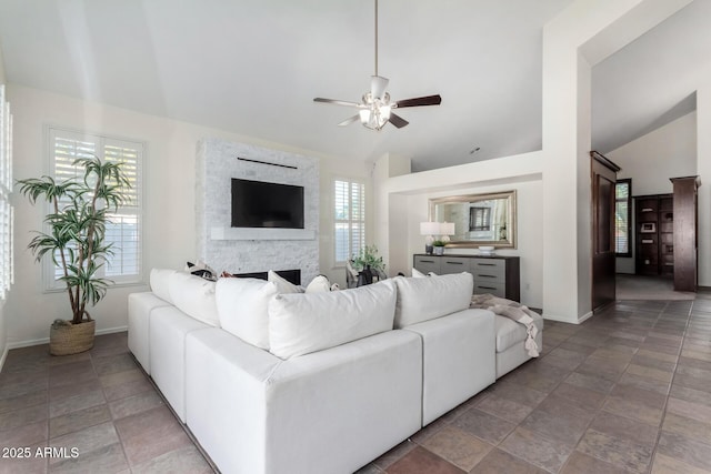 living room with a fireplace, a healthy amount of sunlight, ceiling fan, and lofted ceiling