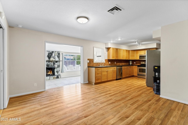 1832 E Concorda Dr, Tempe, AZ 85282 - kitchen with appliances with stainless steel finishes, dark countertops, a sink, light wood finished floors, and decorative backsplash