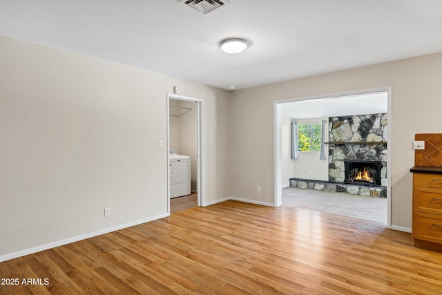 1832 E Concorda Dr, Tempe, AZ 85282 - unfurnished living room with washer / dryer, light wood-style floors, a stone fireplace, and baseboards