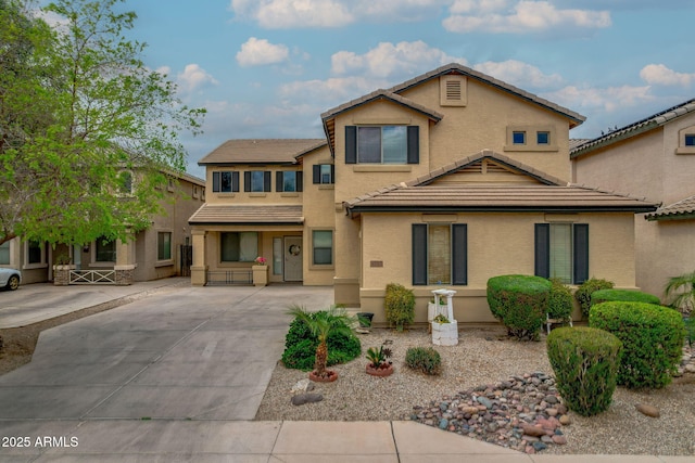 view of front of home featuring stucco siding, a tiled roof, and concrete driveway