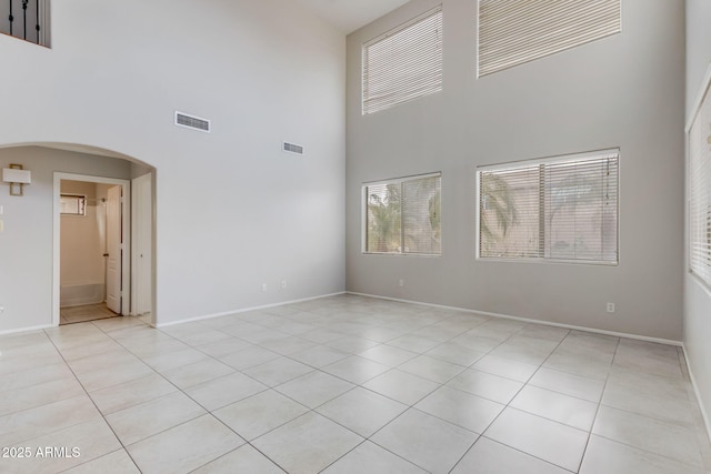 unfurnished room with arched walkways, visible vents, and baseboards