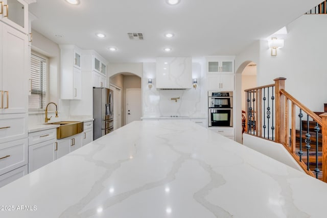 kitchen with arched walkways, visible vents, appliances with stainless steel finishes, and a sink