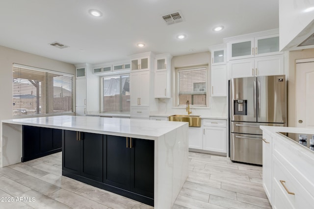 kitchen featuring white cabinets, stainless steel fridge with ice dispenser, visible vents, and a sink