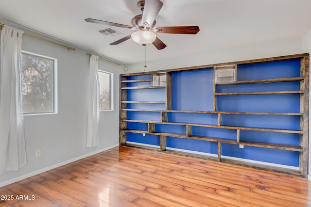 unfurnished bedroom featuring ceiling fan, visible vents, baseboards, and wood finished floors