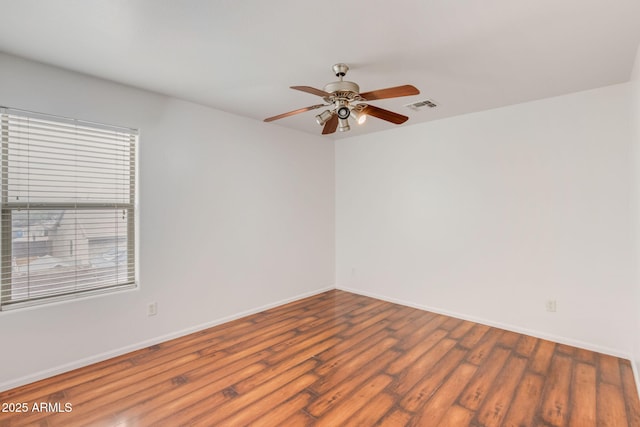 unfurnished room featuring a ceiling fan, wood finished floors, visible vents, and baseboards