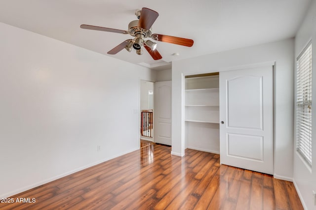 unfurnished bedroom with wood finished floors, baseboards, a closet, and ceiling fan