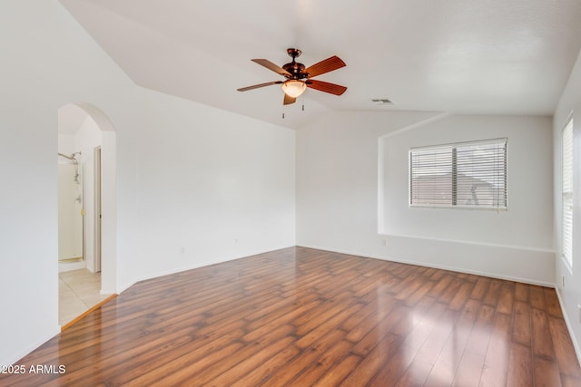 spare room featuring arched walkways, vaulted ceiling, ceiling fan, and wood finished floors