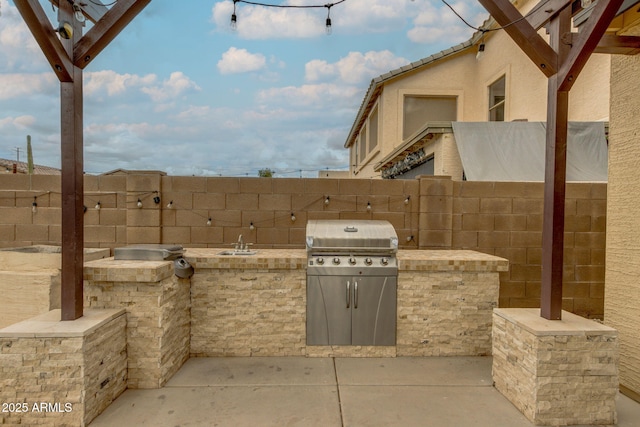 view of patio / terrace featuring a sink, area for grilling, an outdoor kitchen, and fence