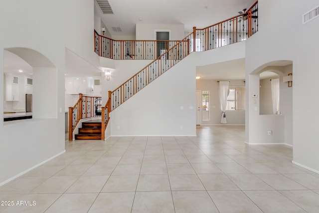 unfurnished living room featuring tile patterned floors, stairway, baseboards, and visible vents