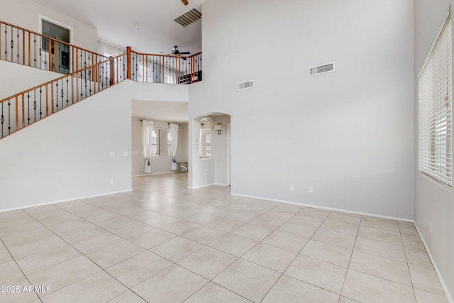 unfurnished living room with visible vents, arched walkways, and a ceiling fan