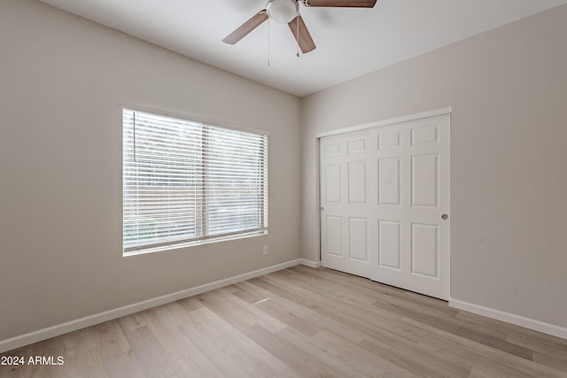 unfurnished bedroom featuring a closet, light hardwood / wood-style flooring, and ceiling fan