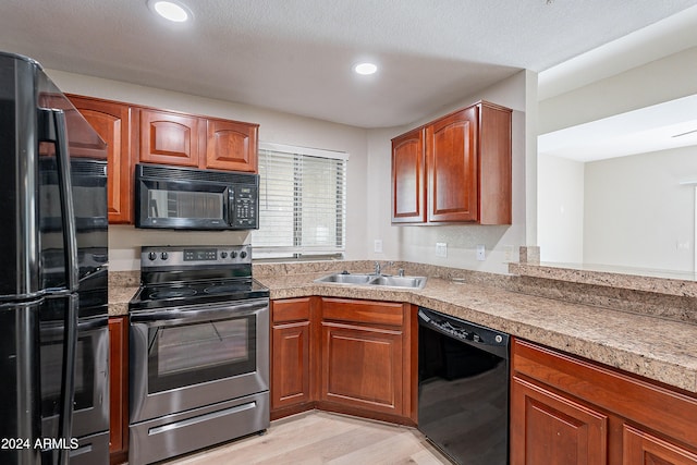 kitchen featuring black appliances, light hardwood / wood-style floors, sink, and a textured ceiling