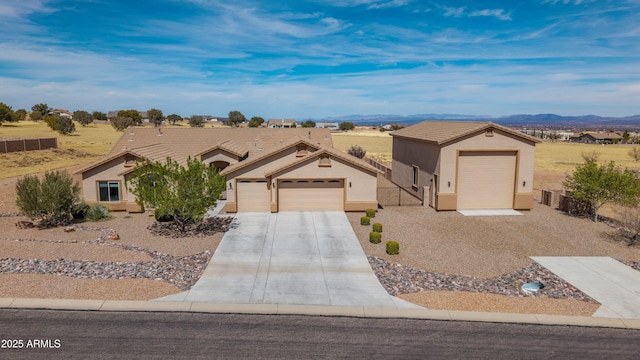 view of front of house featuring a tile roof, stucco siding, fence, and a garage