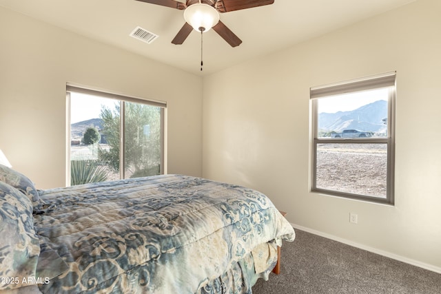 carpeted bedroom with baseboards, a mountain view, visible vents, and a ceiling fan