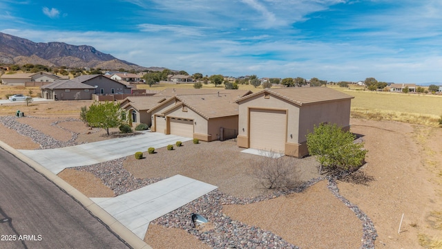 ranch-style home featuring driveway, a tiled roof, a residential view, stucco siding, and a mountain view