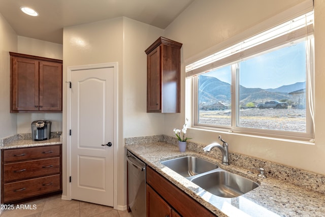 kitchen with light stone counters, a sink, stainless steel dishwasher, light tile patterned floors, and a mountain view