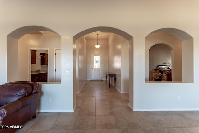 hallway featuring baseboards, a sink, and tile patterned floors