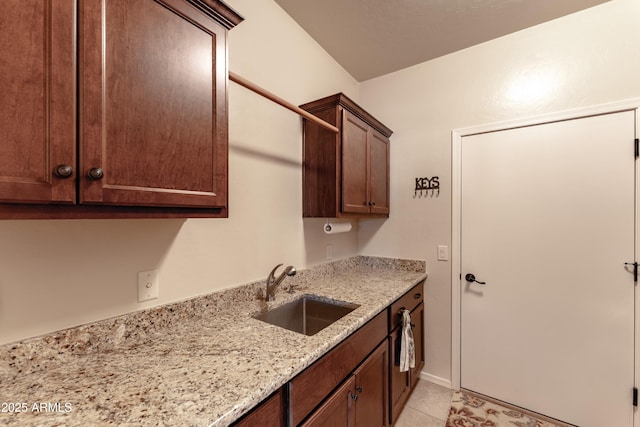 kitchen featuring light tile patterned floors, a sink, and light stone countertops
