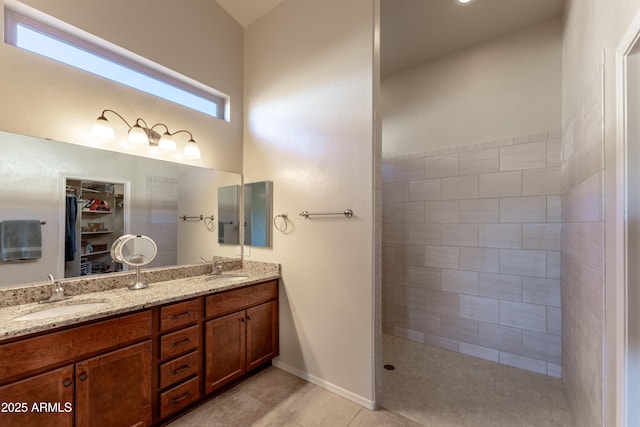 full bathroom featuring double vanity, a sink, a tile shower, and a walk in closet