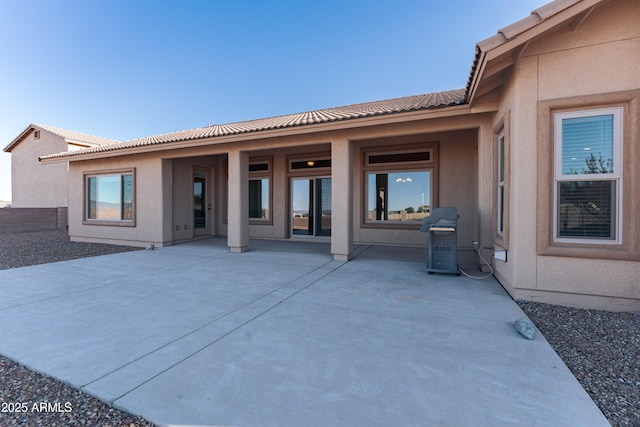 exterior space with a tile roof, stucco siding, and a patio area
