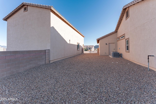 exterior space with central air condition unit, stucco siding, and fence