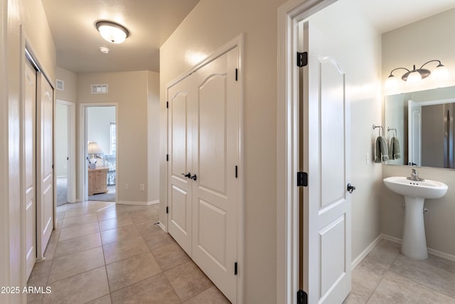 hallway featuring light tile patterned flooring, baseboards, and visible vents
