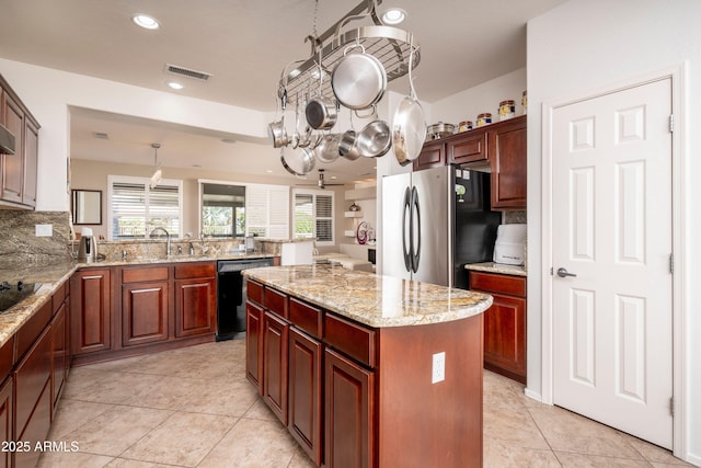 kitchen with sink, hanging light fixtures, tasteful backsplash, black appliances, and a kitchen island