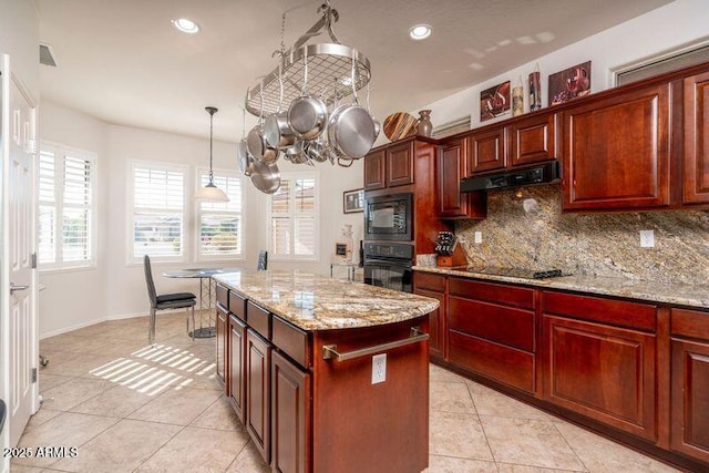 kitchen featuring pendant lighting, a center island, tasteful backsplash, light stone countertops, and black appliances