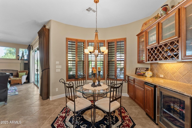 tiled dining room featuring wine cooler, a wealth of natural light, indoor bar, and a notable chandelier