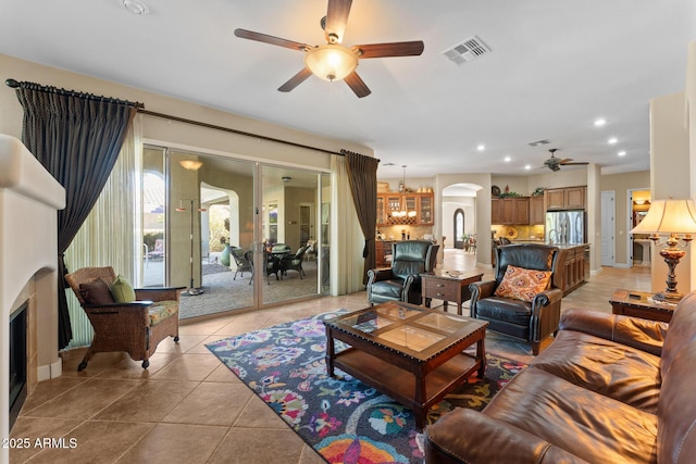 tiled living room featuring ceiling fan with notable chandelier