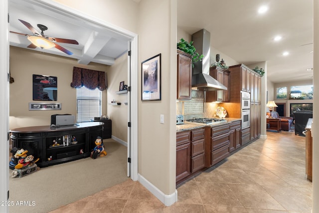 kitchen featuring wall chimney exhaust hood, light colored carpet, plenty of natural light, and stainless steel gas cooktop