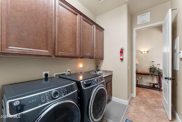 clothes washing area featuring washer and dryer, sink, light tile patterned floors, and cabinets