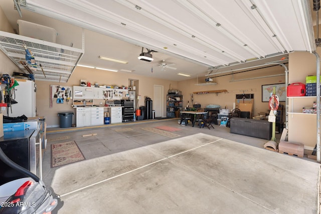 garage with a workshop area, a garage door opener, and ceiling fan