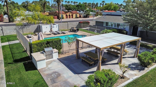 pool featuring a patio area, an outdoor kitchen, a grill, and fence