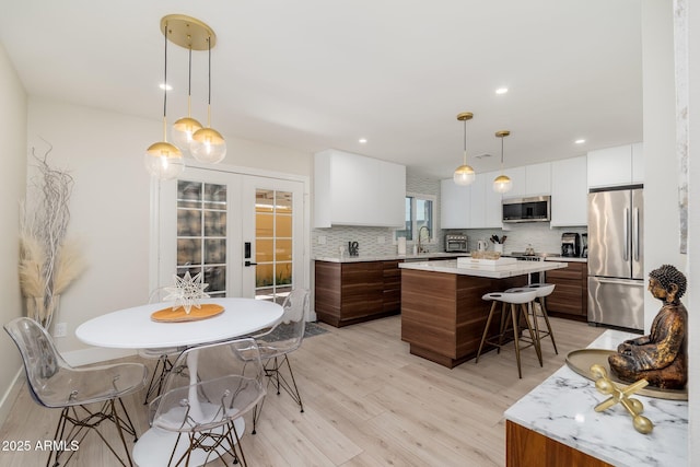 kitchen featuring a breakfast bar, light countertops, appliances with stainless steel finishes, and light wood-style floors