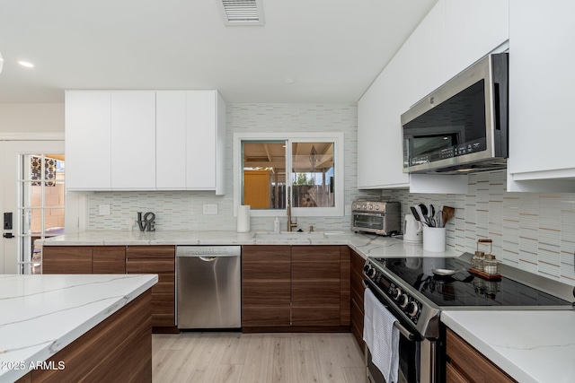 kitchen with appliances with stainless steel finishes, white cabinetry, modern cabinets, and a sink