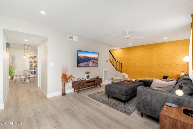 living area with visible vents, light wood-type flooring, stairs, and baseboards