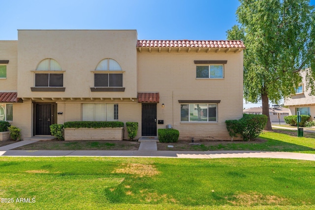 view of front of home featuring stucco siding, a tiled roof, and a front yard