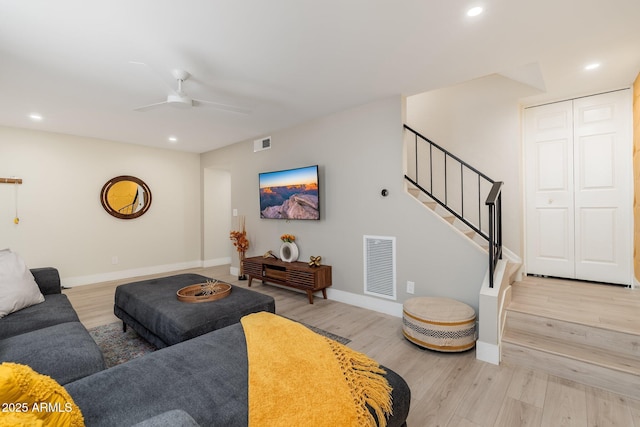 living area with visible vents, light wood finished floors, and stairs