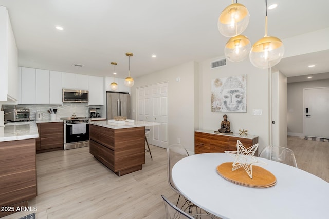 kitchen featuring modern cabinets, white cabinets, appliances with stainless steel finishes, and light countertops